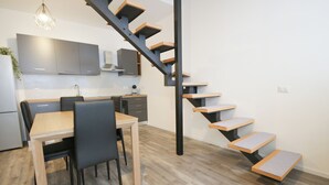 A modern kitchen with grey cabinets, a wooden dining table, and a black staircase with wooden steps. - Sant'Avendrace: Spacious Apt. 3 bedrooms, 2 baths (Cagliari)