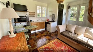 Una sala de estar acogedora con un sofá, una mesa de centro y un televisor. Hay una zona de cocina con estufa, lavabo y armarios.