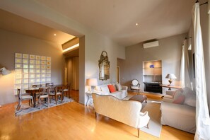 A spacious living room with a dining area, a sofa set, a fireplace, and a television.