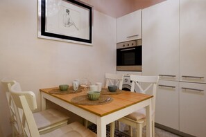 A dining area with a wooden table, white chairs, and a framed picture on the wall.