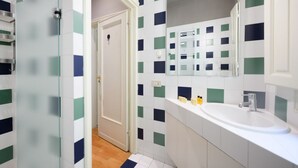 Une salle de bain avec un lavabo blanc, un miroir et des murs recouverts de carreaux disposés en motif à carreaux.