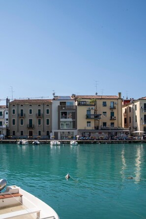 A waterfront view with buildings, a clear sky, and calm water. - Apartment 'Palazzo Cordigero - Bastioni' with Canal View, Wi-Fi and Air Conditioning (Peschiera del Garda)