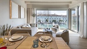 Una sala moderna con comedor, ventanas grandes y vistas a un canal.