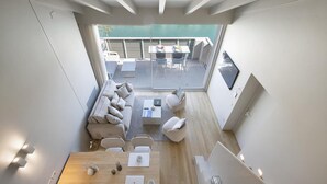 Un interior moderno con comedor, conjunto de sofá y balcón con mobiliario exterior.