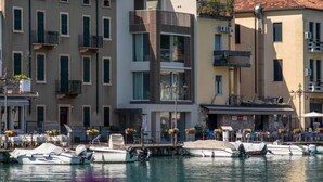 Un edificio frente al agua con balcones, un puerto deportivo con barcos y un cielo despejado.