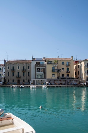 A waterfront view with buildings, a clear sky, and calm water. - Palazzo Cordigero - Canale Apartment with Canal View, Wi-Fi and Air Conditioning (Peschiera del Garda)