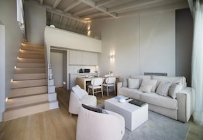 A modern living room with a sofa, a coffee table, and a dining area with chairs.