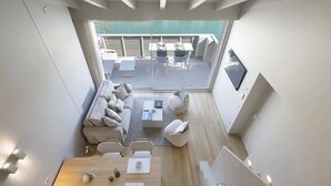Un interior moderno con comedor, asientos y vistas a un balcón exterior.
