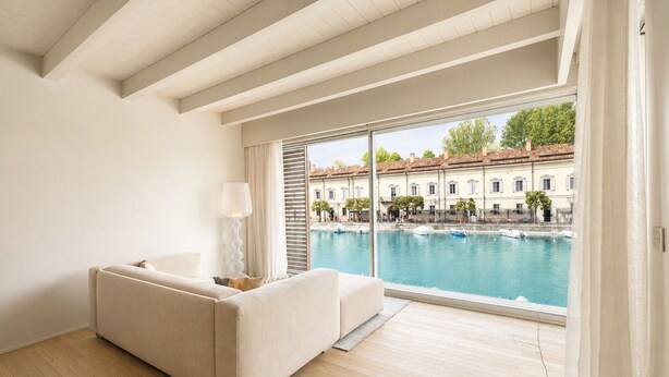 Una habitación moderna con un ventanal grande que da a una piscina y edificios.