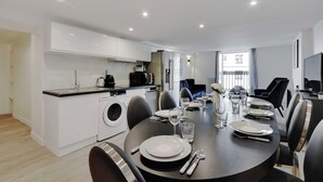 A modern kitchen with white cabinets, a built-in oven, and a dining area with a round table set for four. - Appartement in the Heart of Paris - Opera (Paris)