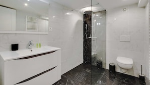 A modern bathroom with a white vanity, a glass-enclosed shower, and a toilet. - Appartement in the Heart of Paris - Opera (Paris)