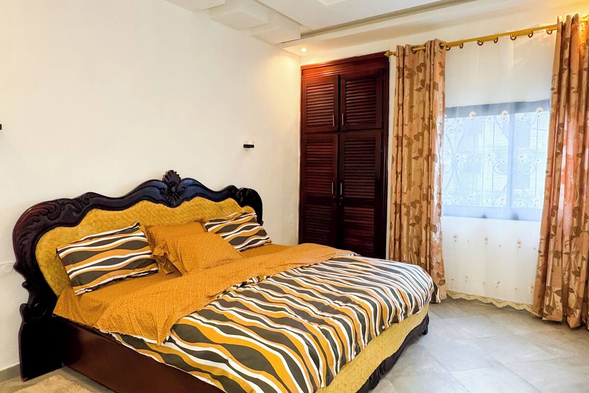 A bedroom with a bed, curtains, a window, and a door.