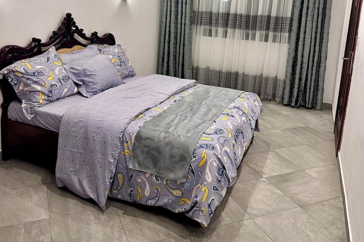 A bedroom with a bed, curtains, and a ceiling light fixture.