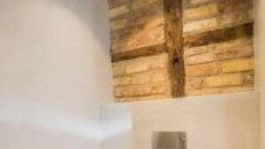 A room with a wooden ceiling, a white wall, and a small window. - Libretto Suites (Lefkada)
