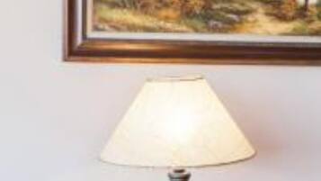 A framed landscape painting with a lamp in front.