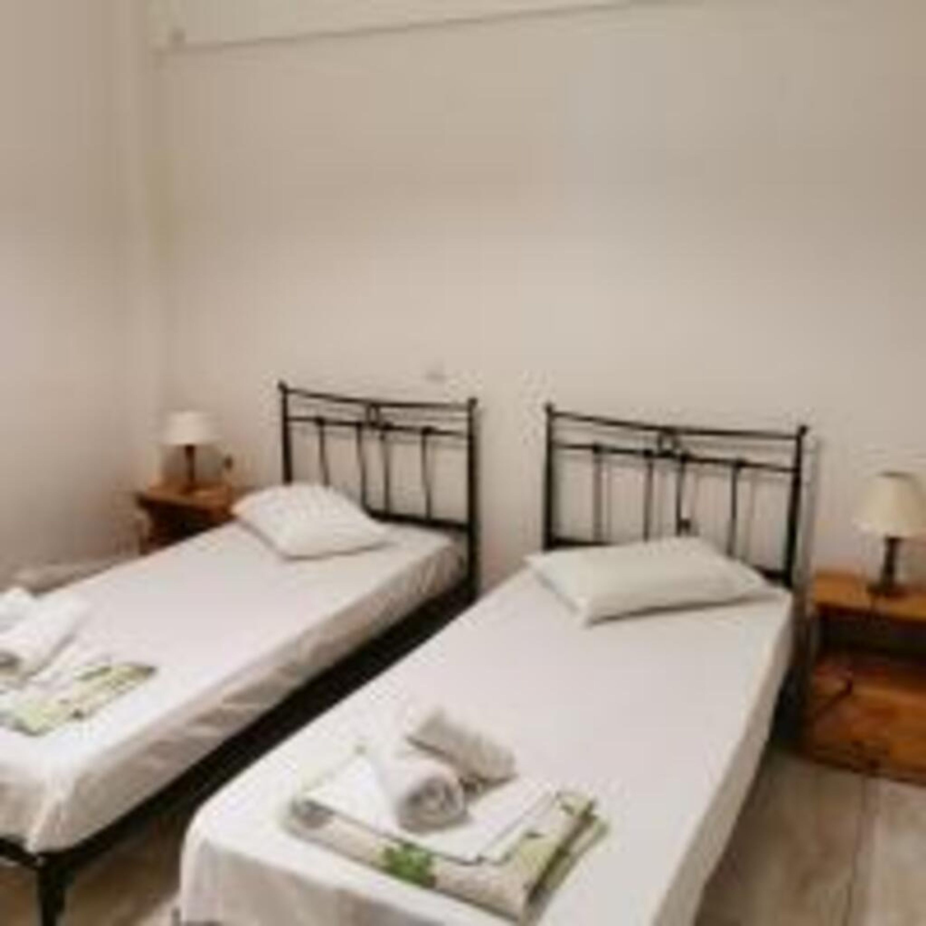 Una habitación con dos camas individuales, cada una con una almohada y una mesita de noche con lámpara.