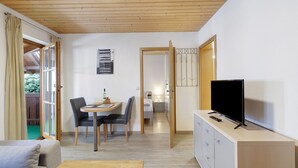 A modern room with a wooden ceiling, a dining area with a table and chairs, a TV on a cabinet, and a sliding glass door leading to an outdoor area. - Apartment 'Haus 3 2-zimmer' with Lake View, Shared Terrace and Wi-Fi (Meersburg)