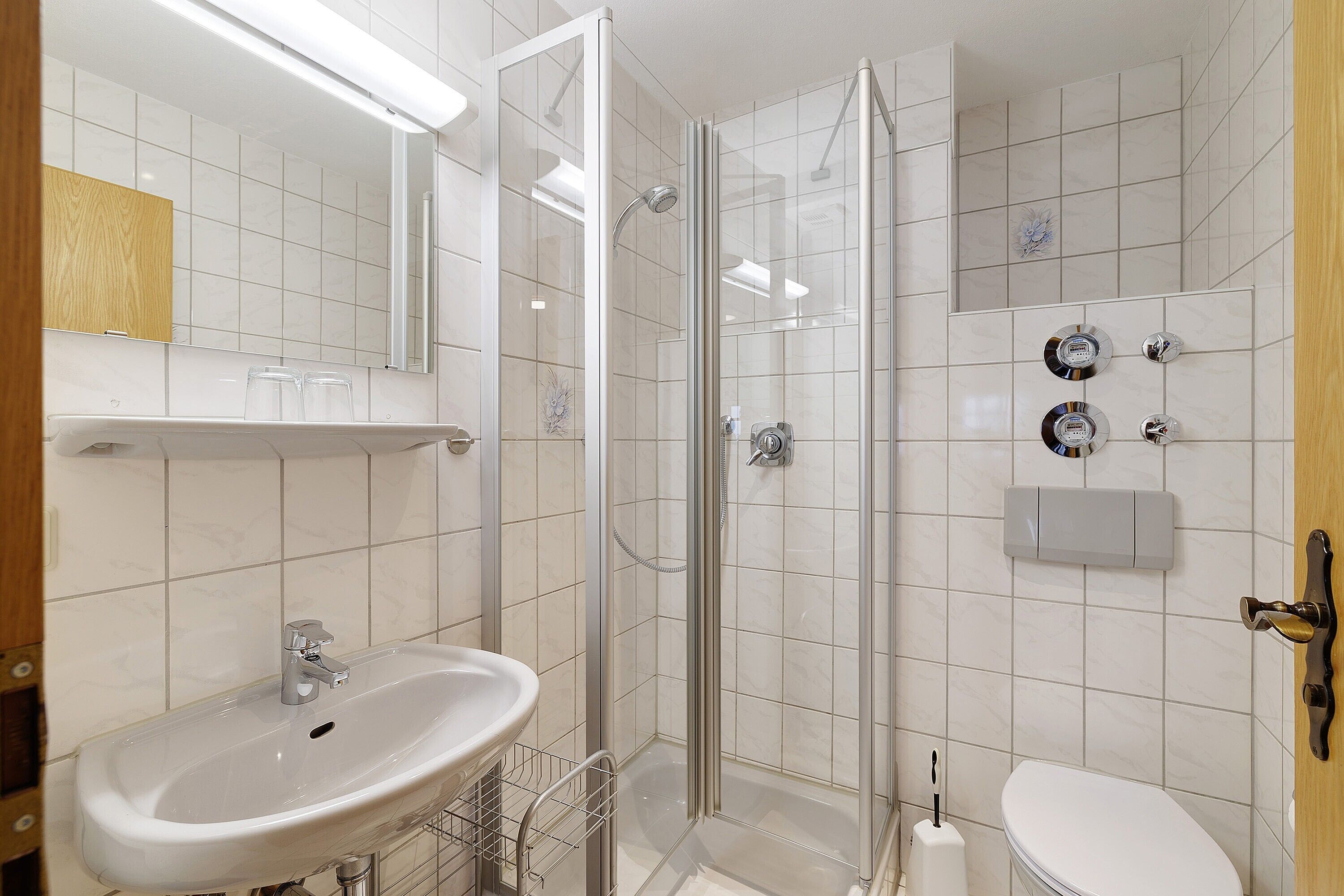 A bathroom with a glass-enclosed shower, a sink, and a toilet.