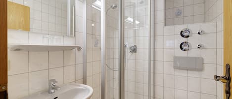 A bathroom with a glass-enclosed shower, a sink, and a toilet.