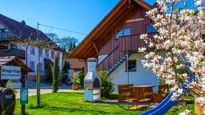 Un edificio de madera con un tobogán azul, una zona de barbacoa y un cartel que indica una Weingut.