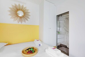 A hotel room with a bed, a fruit bowl, towels, a mirror, and a bathroom with a marble wall. - Intimate Studio - 2P - Arts et Metiers/republique (Paris)