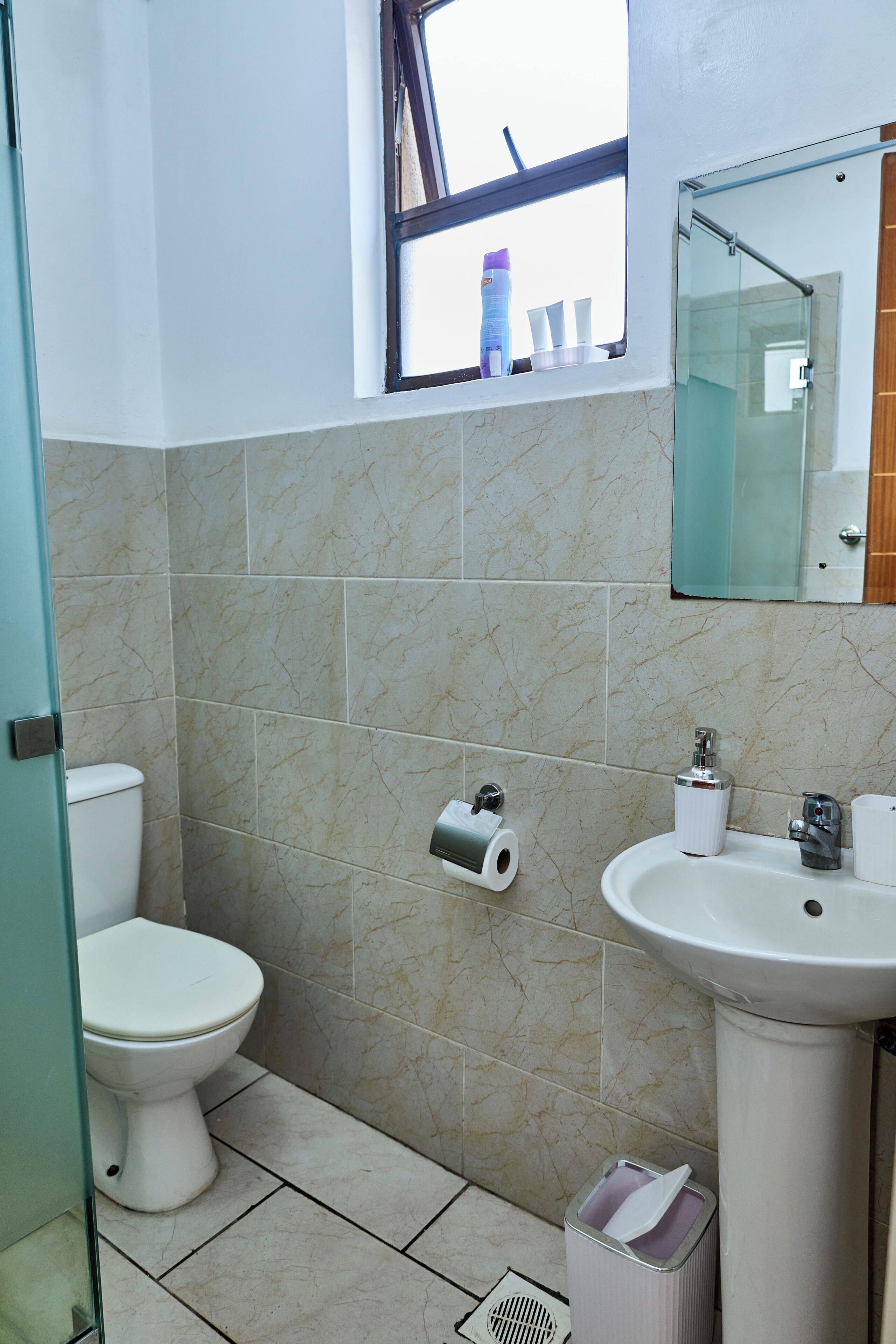 A bathroom with a toilet, sink, and a window.