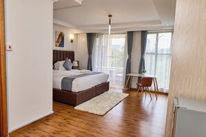 A bedroom with a bed, bedside table, lamp, and a view of the outdoors. - Sangara by Edmor Suites. (Nairobi)