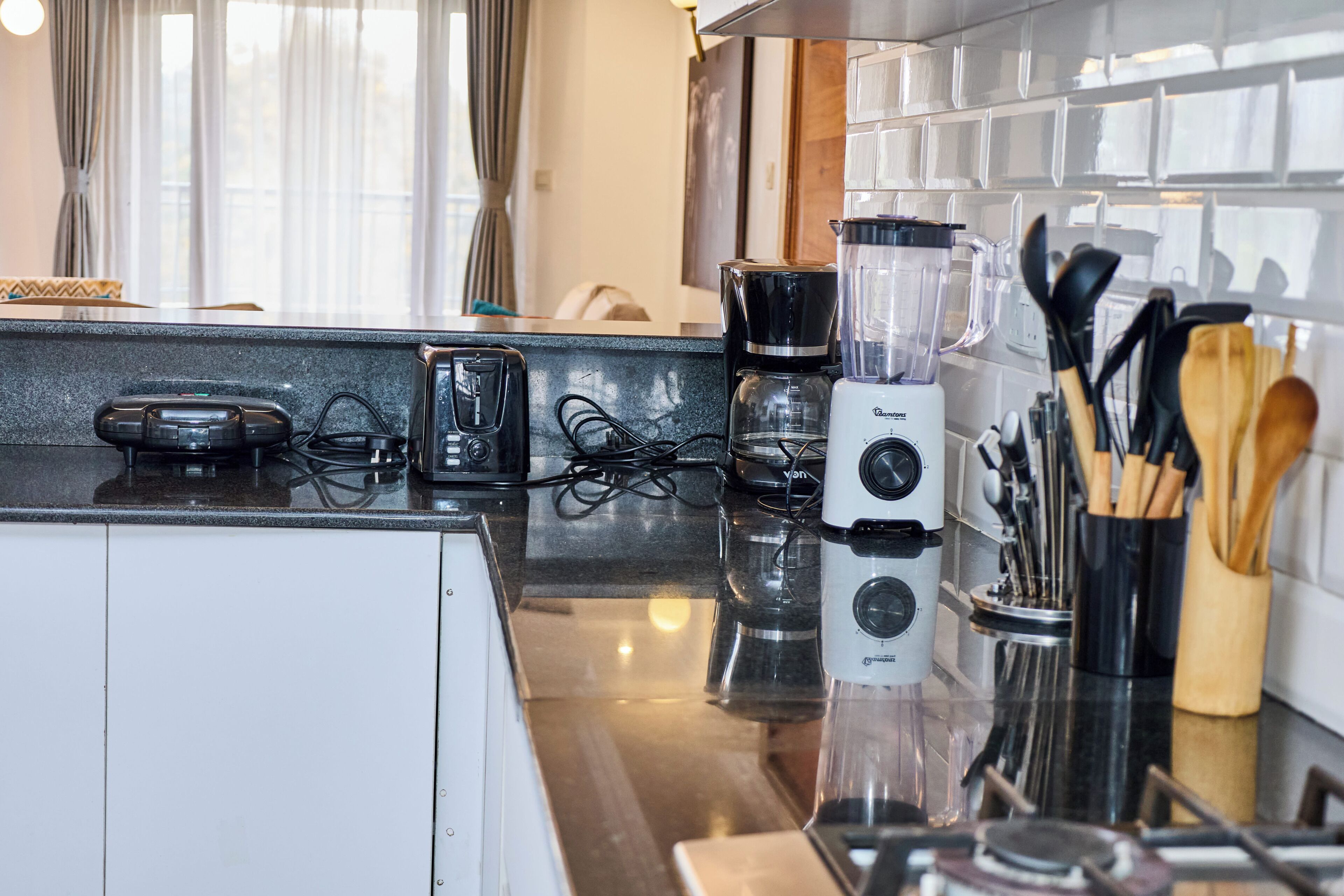 Eine Küche mit Kaffeemaschine, Mixer und Geschirr auf der Arbeitsfläche.