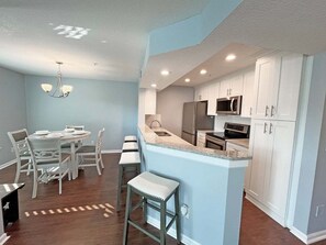 A modern kitchen with white cabinets, a stainless steel refrigerator, and a microwave.