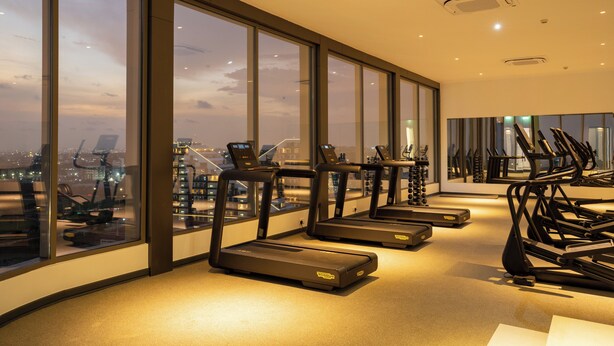 A gym with treadmills and exercise equipment, large windows with a city view, and a modern interior design. - One bedroom Luxury @ Loxwood…..Enjoy! (Accra)