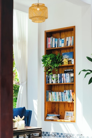 Ein Bücherregal mit Büchern und einer Pflanze, ein blaues Sofa und eine Pendelleuchte.