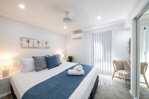 A modern hotel room with a large bed, a desk, and a chair.