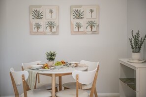 Een eetgedeelte met een ronde tafel, vier stoelen en een potplant op een witte kast.