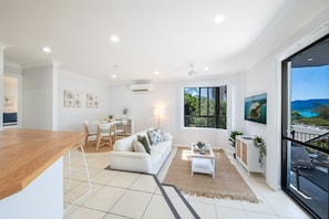 A modern living space with a kitchen area, dining table, and a large window offering a view of the outdoors.