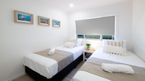 Una camera da letto con due letti, una finestra vista e tre quadri appesi al muro.