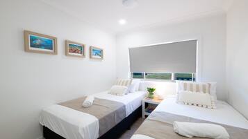 A bedroom with two beds, a window with a view, and three framed pictures on the wall.