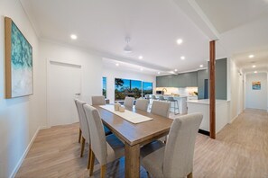 Ein stilvoller Essbereich mit Holztisch und -stühlen, im Hintergrund eine Küche und ein Blick ins Freie.