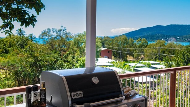 Una griglia Weber con salse e condimenti su un balcone con vista su un paesaggio suggestivo.