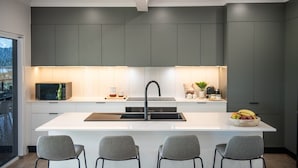 Una cucina moderna con isola centrale, mobili grigi e lavello in acciaio inossidabile.