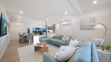 A modern living room with a sofa, coffee table, and dining area.