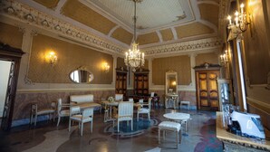 Une vaste pièce agrémentée de lustres somptueux, d’un grand miroir et de meubles classiques.