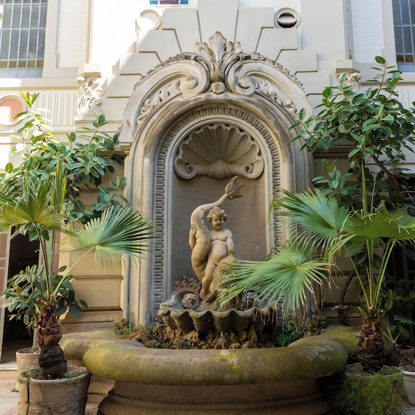 A fountain with a statue of a woman and a child, surrounded by plants. - POSEIDON B&B (Reggio Calabria)