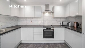 A modern kitchen with white cabinets, a marble backsplash, a built-in oven, and a microwave. - Modern 3 Bed room Apartment with 4 Beds and 2 Full Bathrooms - Sleeps 6 (London)