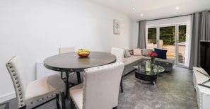 A living room with a dining table, chairs, a sofa, and a coffee table.