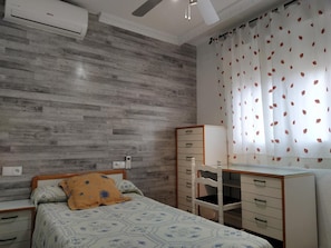 A bedroom with a bed, a dresser, a chair, and a ceiling fan.