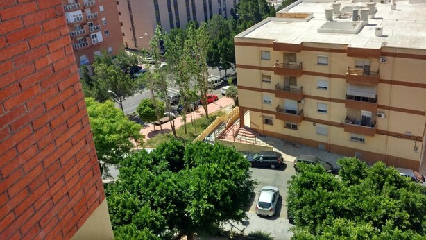 Un immeuble à plusieurs étages doté de balcons, d’un espace de stationnement et entouré d’un paysage urbain.