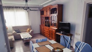 Un salon comprenant un canapé, une table basse, un téléviseur et un meuble en bois.
