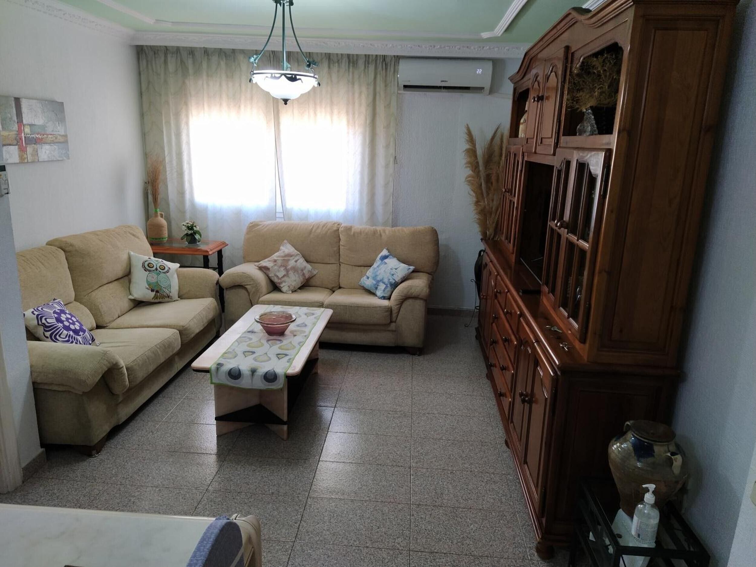 A living room with two sofas, a coffee table, a wooden cabinet, and a ceiling fan.