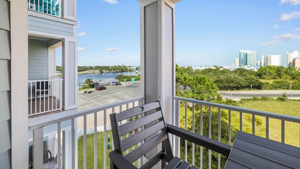 Un balcon offrant une vue sur un plan d’eau, un parking et le paysage urbain.