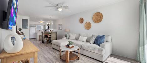 A modern living room with a sofa, a coffee table, and a TV on a stand.